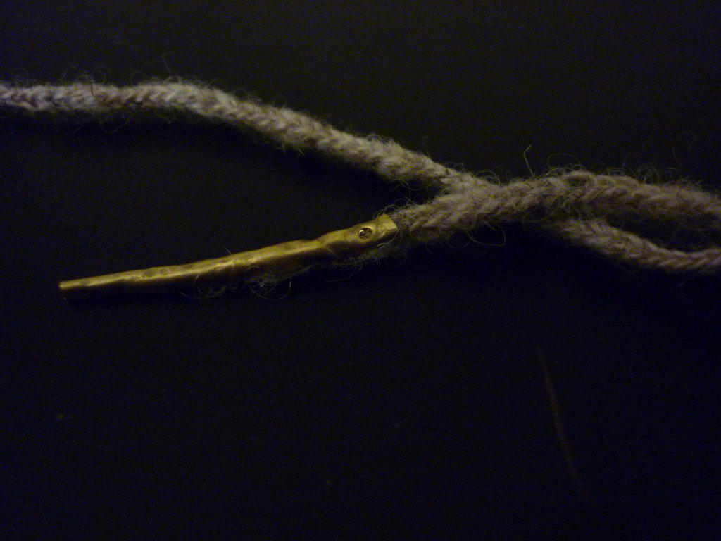 a wool cord with a handmade brass aiglet attached