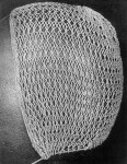 photo of a white hairnet/cap with a gathering thread at the bottom, netted in a pattern of large and small diamonds.