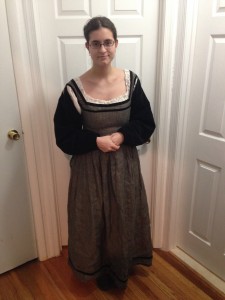 me standing with hands folded wearing a grey dress with gathered skirt, square neck, and black velvet sleeves