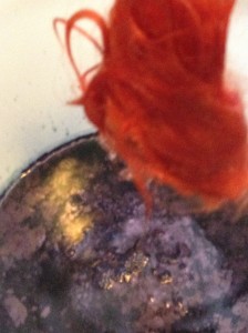 a tuft of red wool hovers over an indigo dyebath