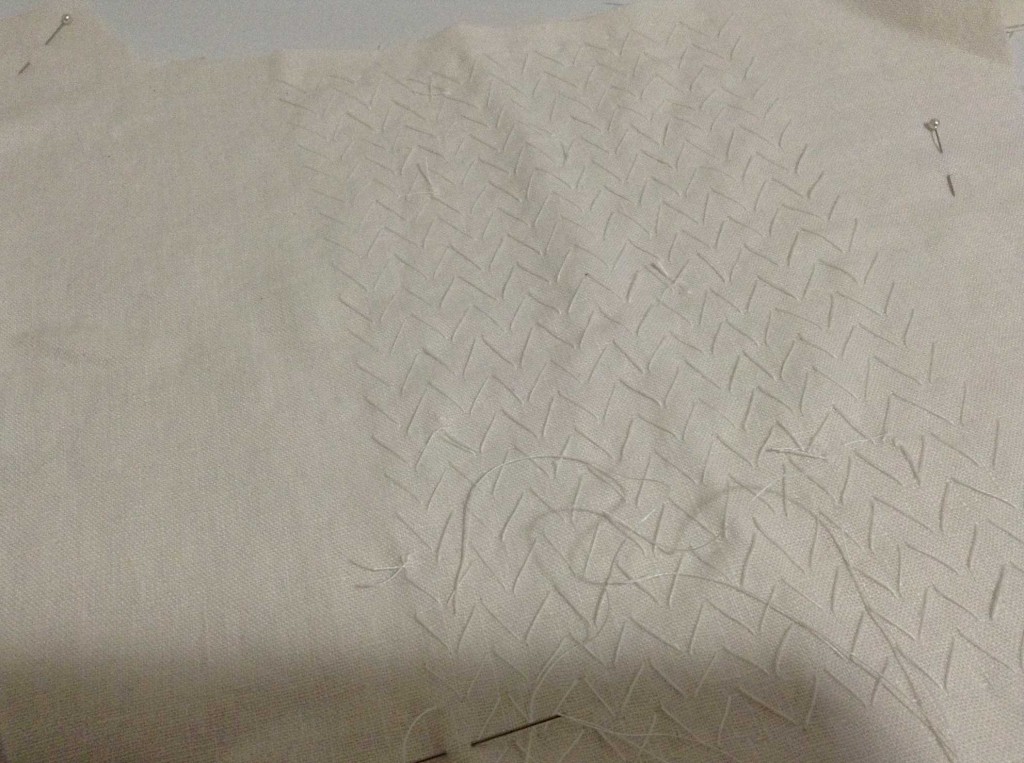 White thread on white linen making large pad stitches