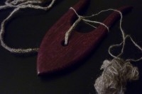 a purpleheart lucet with cord coming out one side and a ball of handspun laceweight wool on the other