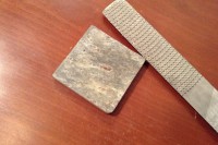 a square of slate and a rasp sitting on a table