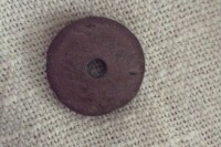 A circle of slate with a hole in the middle, sitting on a piece of cloth