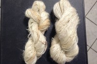 two hanks of thin white yarn on a black background
