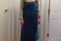 I stand wearing an unbleached linen long-sleeve underdress and a blue wool apron dress